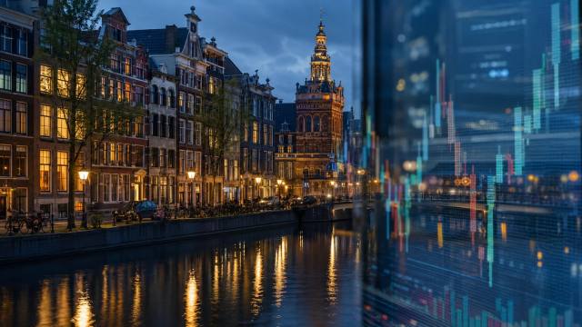 Verlichte Amsterdamse gracht met koersgrafieken