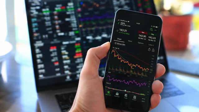 Beleggingsapp op een smartphone naast een laptop